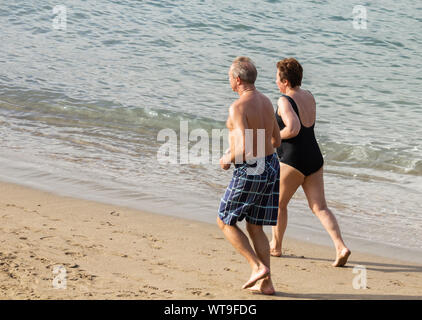 Elderly couple jogging on beach Stock Photo