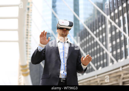 Digital Composite Image Of Businessman Wearing Virtual Reality Simulator While Standing In City Stock Photo