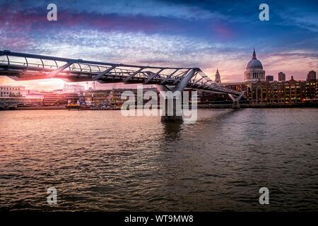 Millennium Bridge Over River Thames By St Pauls Cathedral Against Sky At Sunset