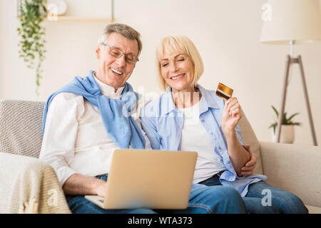 Excited older couple doing online shopping on laptop Stock Photo