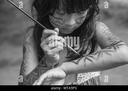 Young indigenous girl from Brazilian Amazon painting her body Stock Photo