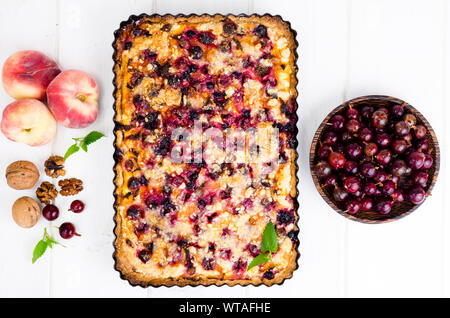 Homemade tart with berries, fruits and walnuts in shape on light background. Studio Photo Stock Photo