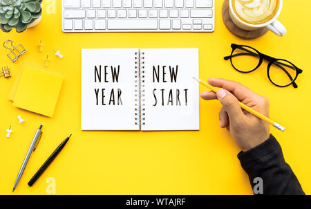 New year new start text with youngman writing on notepad on color desk table.Business goal-plan-action and resolution concepts ideas Stock Photo