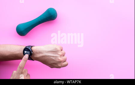 Young man using smartwatch device and fitness program with dumbbell.Sport technology.Modern life and body healthy concepts ideas Stock Photo