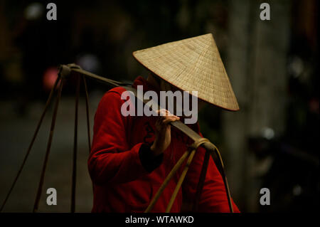 Vietnamese fruit vendor with traditional hat Non La in the streets Stock Photo