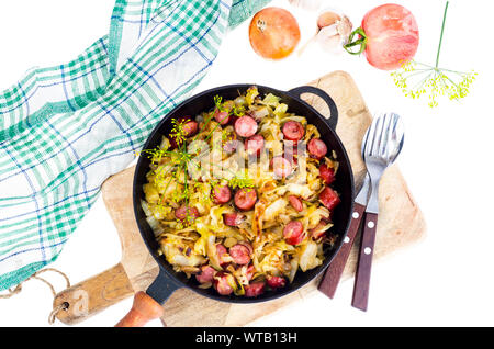 Fried cabbage with smoked sausages in pan. Studio Photo Stock Photo