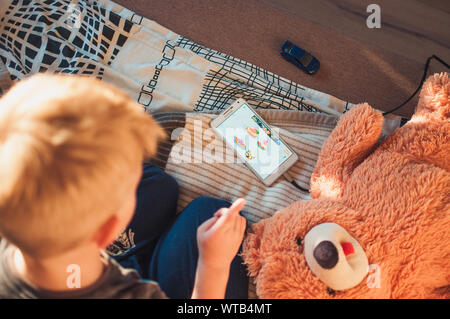 LOS ANGELES, CA, USA - OCTOBER 1, 2018: A phone with an educational game for a 5 year old child lies on the bed. A child plays on the phone, illustrat Stock Photo