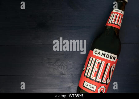 LONDON - SEPTEMBER 3, 2019: Camden Hells craft beer bottle on dark wood background Stock Photo
