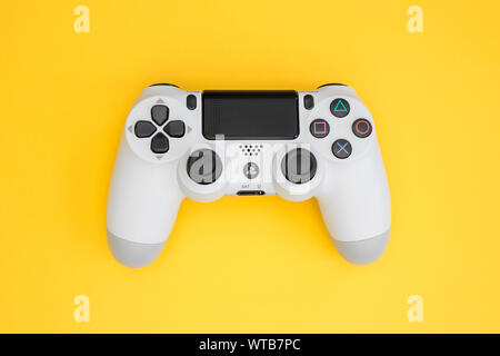 LONDON - SEPTEMBER 06, 2019: Video games PlayStation white gaming controller isolated on yellow color background top view Stock Photo