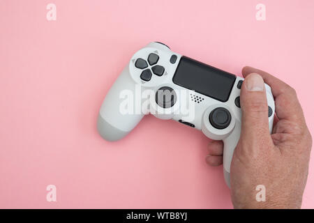 Video games man playing white gaming controller in hands isolated on pink color background top view Stock Photo