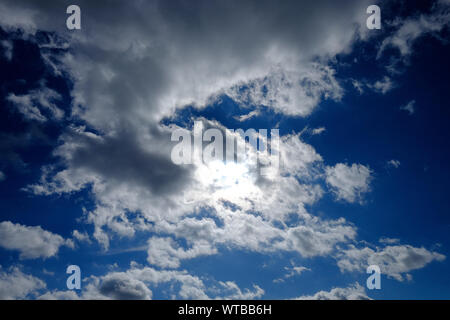 dramatic cloudy blue sky, sun behind clouds, norfolk, england Stock Photo