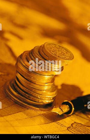 Stack of Coins Sitting on a Map beside a Fountain Pen Stock Photo