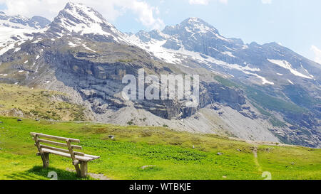 Beautiful natural landscape, summer mountain landscape over the snowy mountain range dolomite italy with wooden bench and green meadow in nature backg Stock Photo