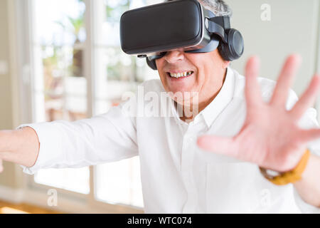 Man wearing virtual reality glasses smiling looking very happy and excited Stock Photo