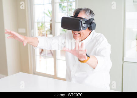 Man wearing virtual reality glasses smiling looking very happy and excited Stock Photo
