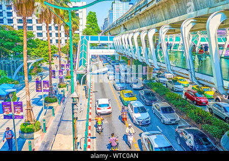 BANGKOK, THAILAND - APRIL 24, 2019: The modern pedestrian skywalk along busy Ratchaprasong road with the line of (BTS) Skytrain above, on April 24 in Stock Photo