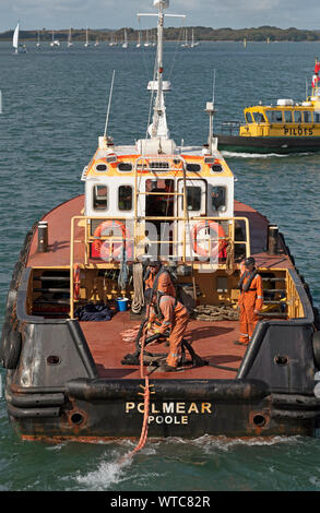 Poole Harbour, Dorset, England, UK. September 2019.  Tug crew pulling in line from a vessel they have just pulled from a berth. Stock Photo