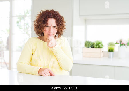 Beautiful senior woman wearing yellow sweater feeling unwell and coughing as symptom for cold or bronchitis. Healthcare concept. Stock Photo