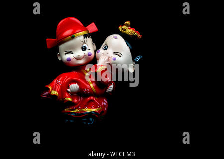Small Chinese wedding figurines isolated against a black background Stock Photo