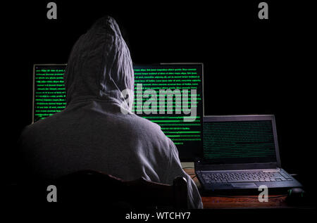 Women hacker breaks into government data servers and Infects Their System with a Virus at his hideout place has dark blue atmosphere,  Lady hooded usi Stock Photo
