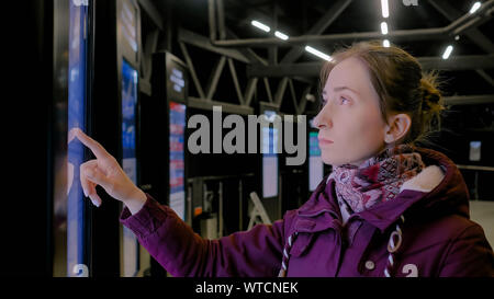 Woman using interactive touchscreen display of electronic multimedia kiosk Stock Photo