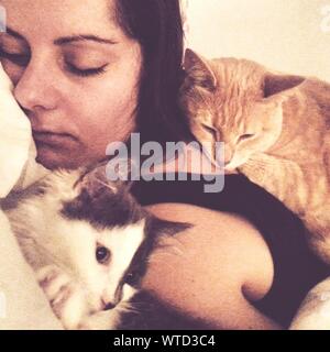 Close-up Of Young Woman Sleeping With Pet Cats