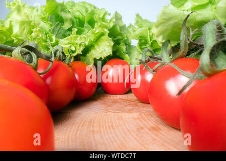 Red cheery tomatoes with lettuce leafs on top of wooden table background. Home grown vegetables, healthy eating lifestyle Stock Photo
