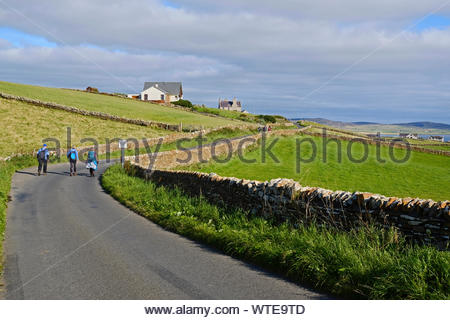 Walkers on Outertown Road with a view towards Stromness Orkney, Scotland Stock Photo