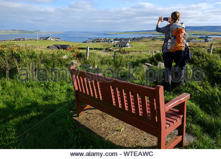 Walker taking a photograph from Outertown Road with a view towards Stromness Orkney, Scotland Stock Photo
