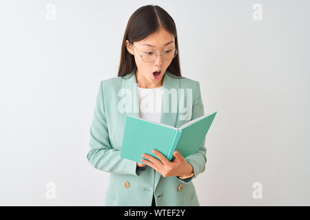Young chinese student woman wearing glasses reading book over isolated white background scared in shock with a surprise face, afraid and excited with Stock Photo