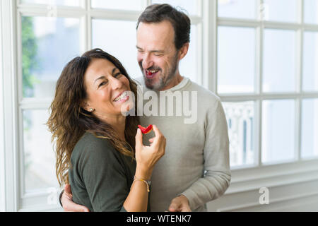Middle age senior couple eating a fresh strawberry at home Stock Photo