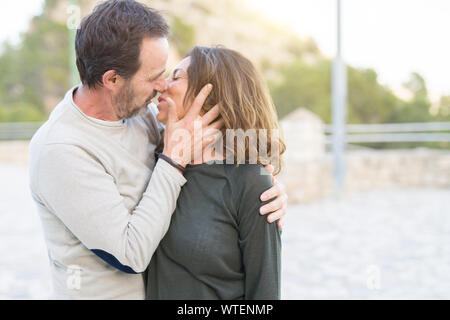 Romantic couple smiling and cuddling kissing in love on a sunny day Stock Photo