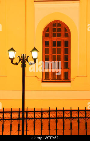 Vintage style gorgeous street lamp against vivid yellow rough wall with antique window. Background. Stock Photo