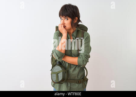 Beautiful hiker woman wearing backpack and water canteen over isolated white background looking stressed and nervous with hands on mouth biting nails. Stock Photo