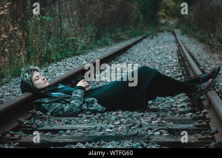 Young Woman Lying On Railroad Track