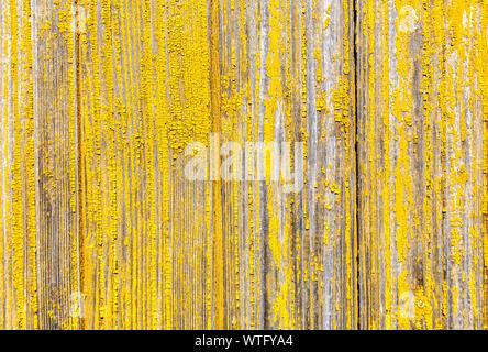 Old rough wooden boards with cracks as background. Wooden planks texture with the shabby yellow paint Stock Photo
