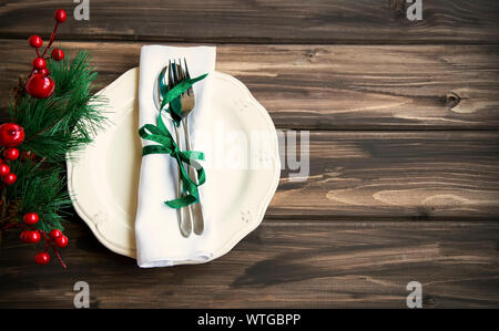 Festive Christmas table setting with white plate, tableware, ribbon on wooden rustic table background, top view Stock Photo