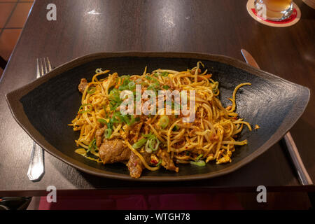 A bami goreng (beef, chicken in noodles), an Indonesian dish, as served in a Munich, Bavaria, Germany Asian food restaurant. Stock Photo