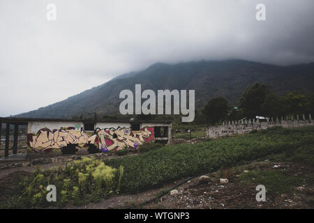 Graffiti on Building in Front of Cloud Covered Volcano in San Pedro la Laguna, Guatemala Stock Photo