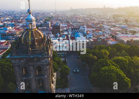 Puebla city pass at sunrise and aerial view of the Basilica or Cathedral of Our Lady of the Immaculate Conception, is the episcopal seat of the archdiocese of the historic and zocalo center of Puebla, Mexico. They have Mexican traditions: gastronomic, colonial architecture and ceramics. Painted talavera tiles adorn ancient buildings. The cathedral of Puebla, in Renaissance style, has a high-rise bell tower overlooking the Zocalo, the central square or zocalo. I enter historical. Architecture is a UNESCO World Heritage Site. Attractions: Cathedral, Temple of Our Lady of Concord, Former Carolino Stock Photo