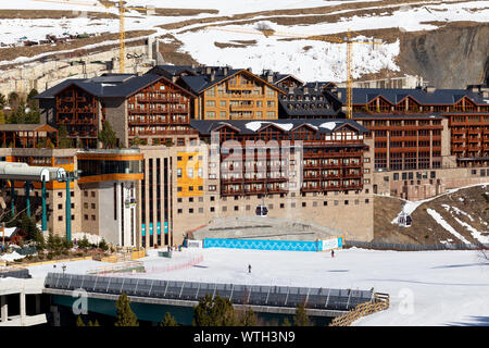 PYRENEES, ANDORRA - FEBRUARY 13, 2019: Multi-storey hotel buildings at the foot of the mountain and ski slopes in the ski resort. Sunny winter day, ro Stock Photo