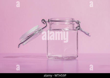 https://l450v.alamy.com/450v/wth59p/empty-glass-jar-with-open-lid-and-metal-clasp-on-a-pink-background-wth59p.jpg