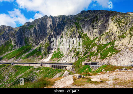 Gotthard Pass with National Road 2 running along steep cliffs of the Alps, protected with a concrete cover against falling rocks. Tessin, Switzerland. Stock Photo