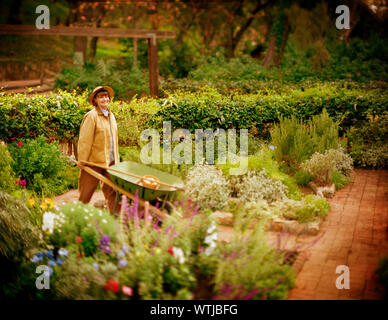 Portrait woman pushing wheelbarrow garden Stock Photo - Alamy