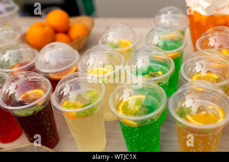 A counter with multi-colored fruit cocktails in plastic cups. Food and cooking equipment at a street food festival. Stock Photo