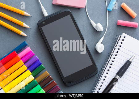 Smartphone and school supplies on desk Stock Photo