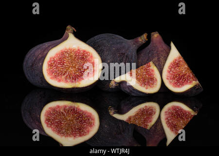 Group of three whole one half two slices of fresh fig fruit isolated on black glass Stock Photo