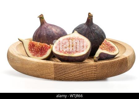 Group of two whole one half two slices of fresh fig fruit on bamboo plate isolated on white background Stock Photo