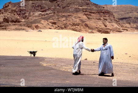 Two men shaking hands in the desert. Stock Photo