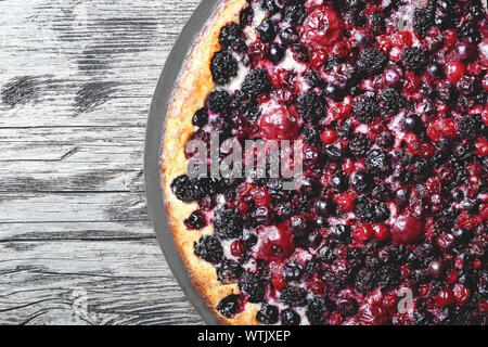 Berry pie with fresh and cream on murble table with cherry, currant, blackberry, blueberry. Cheesecake, top view, close up with copy space. Stock Photo